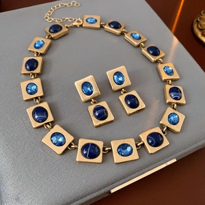 Detail eines Vintage-Schmucksets in Gold mit blauen Edelsteinen auf grauer Box