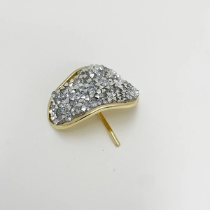Macro shot of fan-shaped hair clip with gold metal base and silver glitter finish