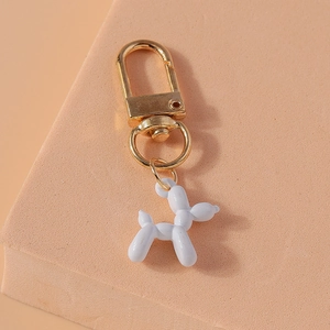 Close-up of a light blue balloon dog keychain with a polished gold ring on pink texture