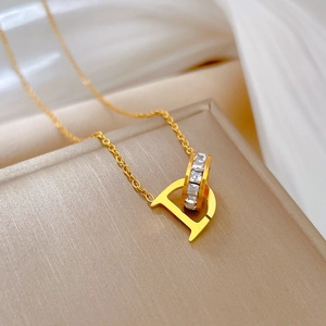Macro detail of gold-plated D-letter pendant necklace with shimmering square zircons