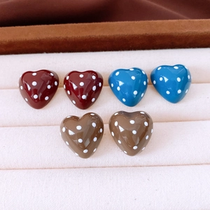 Detailed view of heart-shaped polka dot earrings in burgundy, royal blue and brown
