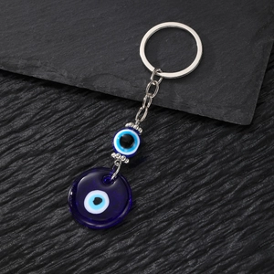 Vintage evil eye keychain with blue glass pendant and metal chain on stone background