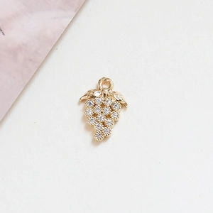 Detailed macro of a gold grape pendant with sparkling cubic zirconia on textured paper