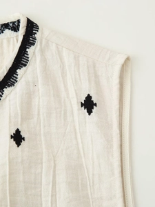 Close-up of geometric black embroidery on a cream linen sleeveless vest for women