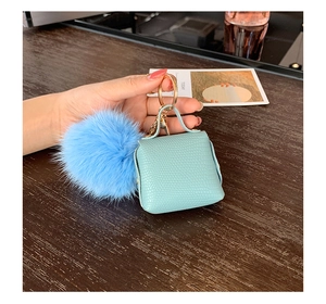 Detail of mint green crocodile pattern mini bag keychain with blue fluffy fur ball pompom