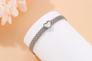 Detail of multi-layer silver heart bracelet with white mother of pearl inlay on display