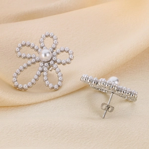 Detailed macro view of silver flower earrings with white pearls on premium satin