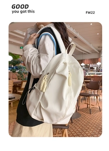 Close-up of white high-capacity backpack featuring decorative woven rope zipper pulls