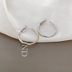 Close-up of minimalist silver hoop earrings on elegant silk background fabric