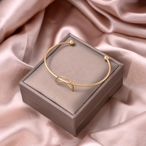 Detailed shot of gold hollow moon bracelet on silk background with polished finish