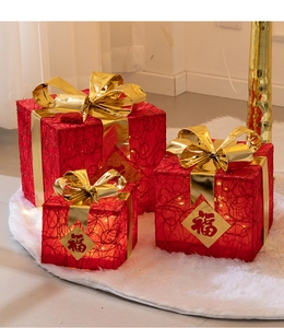 Close-up of red mesh Christmas gift boxes with gold ribbons and warm glowing LED lights