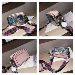 Close-up of pink graffiti camera bag with colorful wide strap and leather details