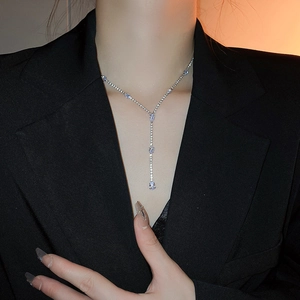 Detail of silver Y-shaped drop necklace with blue and clear rhinestones on model