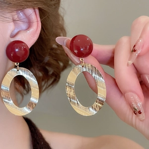 Close-up of vintage drop earrings with burgundy resin beads and brushed gold metal rings