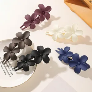 Five matte-finish floral hair clips in assorted colors on a white decorative tray