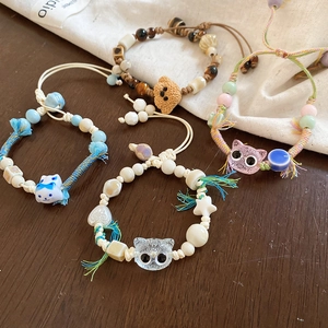 Close-up of four handmade ceramic bead bracelets with cute cat and bear charms