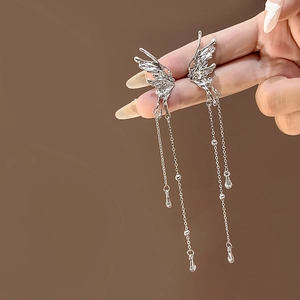 Close-up of elegant silver butterfly earrings with long chain tassels on a brown background