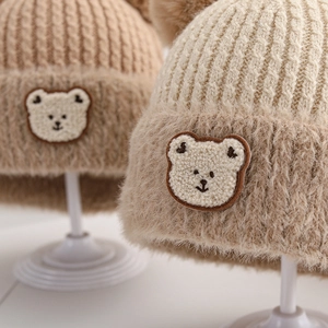 Close-up of knit winter hat with fuzzy brim and a cute bear patch for toddlers