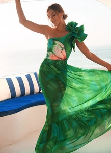 Detail of pink butterfly print and tiered ruffle hem on a green one-shoulder beach dress