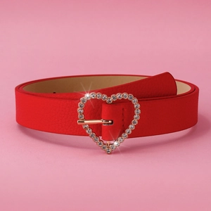 Detail of red leather belt featuring a golden heart-shaped buckle with sparkling rhinestones