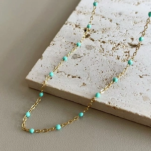 Detail shot of golden necklace with turquoise beads on natural stone surface