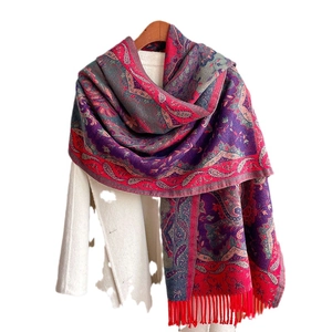 Ethnic style paisley shawl wrap with colorful patterns and red tassels on white background