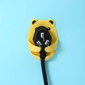 Cute yellow bear wall hook holding a black power plug for tidy wire management