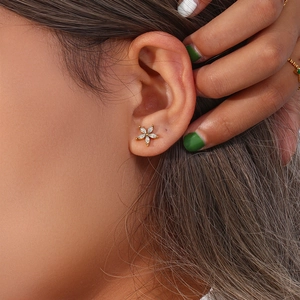 Detailed view of gold plated five-petal flower earring with marquise cut zircon on ear