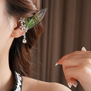 Dettaglio di ear cuff con fiore di cristallo e ala verde su modella con nappa delicata