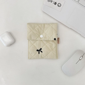 Detail of beige quilted makeup bag with black bow embroidery and secure snap button