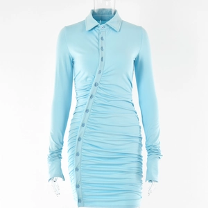 Détail de la robe courte bleue à manches longues avec boutons asymétriques et plis