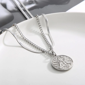 Detailed view of silver double-layered necklace with a religious heart pendant in a white tray