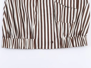 Detail of striped shirt with elastic hem, button closure and flap chest pocket