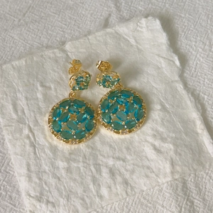Macro view of gold-plated double hoop earrings with turquoise stones and white zircons