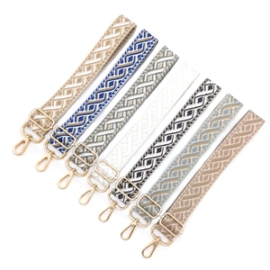 Détail de bandoulières jacquard géométriques avec mousquetons en métal doré poli