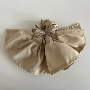 Detailed view of khaki pleated ruffles on a soft fabric scrunchie with a skirt-like texture