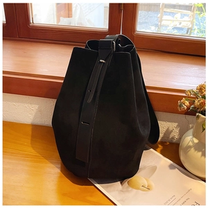 Close-up of black suede tote bag with adjustable strap on a cozy wooden windowsill