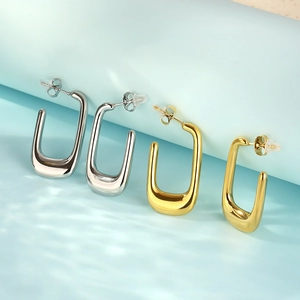 Close-up of gold and silver U-shaped stainless steel earrings with polished finish
