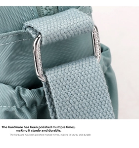 Close-up of silver metal buckle and nylon shoulder strap on light blue crossbody bag