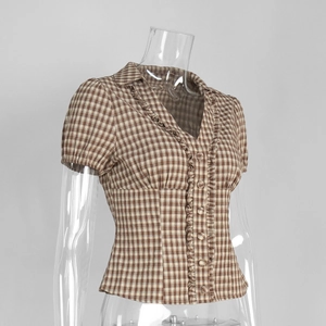 Detail of ruffle trim and V-neckline on brown gingham check short sleeve shirt