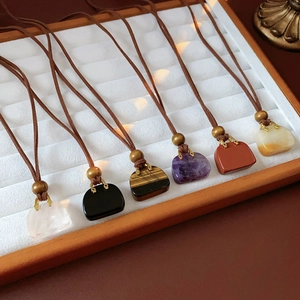 Detail of assorted gemstone bag charms with wooden beads on brown leather cords
