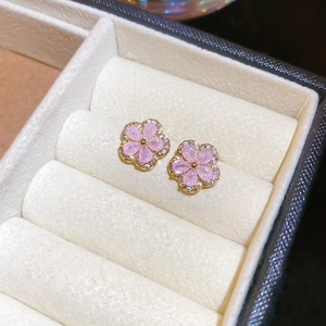 Macro detail of pink flower earrings with sparkling crystals and gold plating