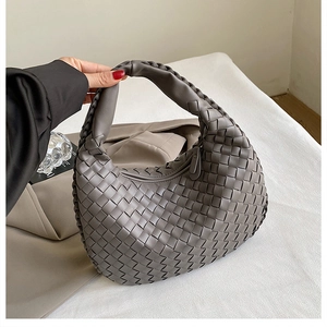 Detail of grey hand-woven leather tote bag with integrated knot handle and crescent shape