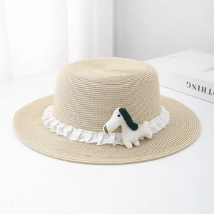 Detail of straw flat top hat featuring white lace trim and a cute stuffed puppy ornament