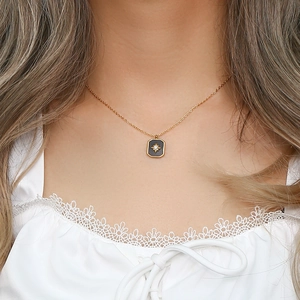 Close-up of a gold necklace with an octagonal black pendant featuring a sparkling star