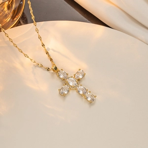 Close-up of golden cross pendant with oval cubic zirconia and unique petal chain