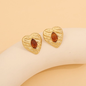 Detail of vintage heart-shaped gold studs with amber stones on minimalist support