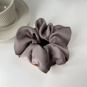 Detailed close-up of taupe silk scrunchie showing elegant satin texture and soft folds