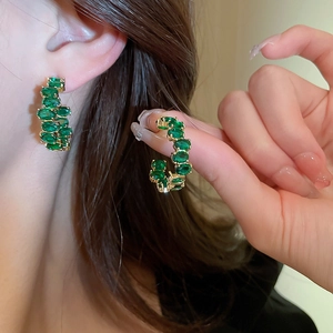 Orecchini a cerchio a C vintage dorati con strass verdi su modella femminile