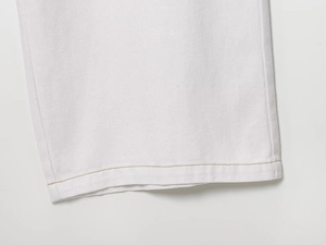 Détail du jogging en denim blanc montrant les coutures précises et la texture du tissu sergé